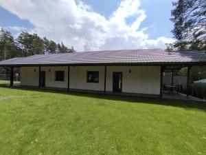 a small white house with a grass yard at Apartament Szum in Susiec +3 photos