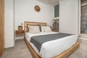 una camera da letto con un grande letto con lenzuola e cuscini bianchi di Thea Suites Naxos ad Agios Prokopios