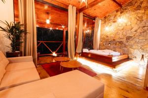 a living room with a couch and a stone wall at Pousada Chale Luiz in Santo Antônio do Pinhal