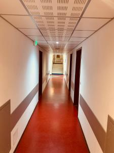 a hallway with a red floor and a ceiling at Terres de France - Résidence Côté Provence in Gréoux-les-Bains