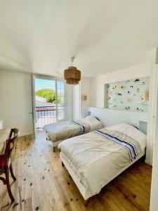 2 Betten in einem Schlafzimmer mit Balkon in der Unterkunft La Villa Archipel Royan Suites & Pool Tennis in Saint-Sulpice-de-Royan