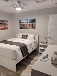 a white bedroom with a bed and a ceiling fan at Cape Breton Flats in Inverness