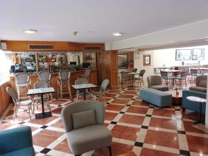 a lobby with chairs and tables and a bar at Suites del Bosque Hotel in Lima