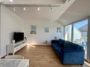 a living room with a blue couch and a tv at Osada Cetniewo by Q4Apartments in Władysławowo