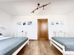 two beds in a bedroom with white walls and wooden floors at Osada Cetniewo by Q4Apartments in Władysławowo
