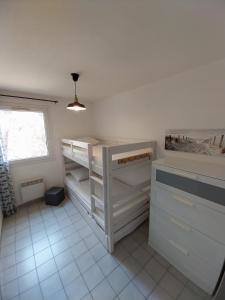 Cette chambre comprend 2 lits superposés et une fenêtre. dans l'établissement T3 capacite 6 personnes dans residence avec piscine et garage, à Sète