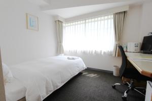 a hotel room with a bed and a desk and a window at Smile Hotel Tokyo Tamanagayama in Tama