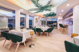a restaurant with white tables and green chairs at Grand Horizon Luxury Boutique Apartments in Puerto Rico de Gran Canaria