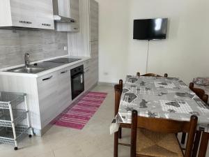 een keuken met een tafel en een keuken met een wastafel bij SA DOMU DE S'ORTU in Bari Sardo