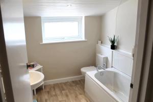 a bathroom with a sink and a toilet and a window at Cosy Cottage in Mersea - Walking distance to beach and town in West Mersea