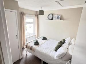a bedroom with a bed with a clock on the wall at Cosy Cottage in Mersea - Walking distance to beach and town in West Mersea