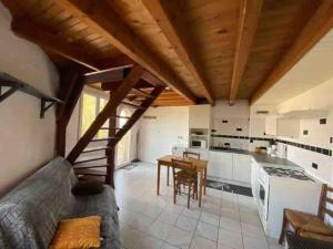 a large kitchen with white walls and wooden ceilings at Petite maison avec terrasse in Sainte-Colombe-de-Peyre