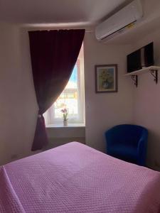 una camera con letto viola e finestra di La casa Azzurra a Ischia
