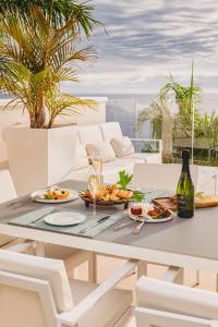 a table with plates of food and a bottle of wine at Grand Horizon Luxury Boutique Apartments in Puerto Rico de Gran Canaria