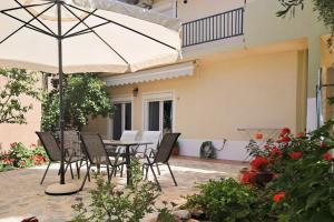 een patio met een tafel en stoelen en een parasol bij Marinos' Place in Skala Kallirakhis