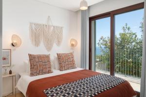 a bedroom with a bed and a large window at Islander - Funchal Seaside Villas in Funchal +27 photos