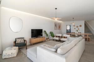 a living room with a white couch and a tv at Islander - Funchal Seaside Villas in Funchal