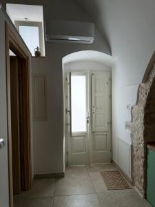 einen Flur mit einer weißen Tür und einem Fenster in der Unterkunft Al Murigini - Casa Vacanze in Ceglie Messapica