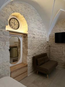 ein Wohnzimmer mit einer Uhr und einer Couch in der Unterkunft Al Murigini - Casa Vacanze in Ceglie Messapica + 25 Fotos