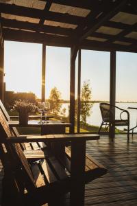 una mesa de madera y sillas en una terraza con vistas al agua en Doles skati en Salaspils