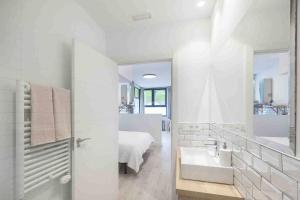 ein weißes Bad mit einem Waschbecken und einem Bett in der Unterkunft LUR Apartments Getaria in Getaria