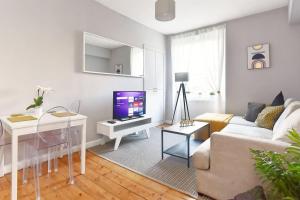 a white living room with a couch and a tv at Cosy and Chic, Quiet Apartment in Leith in Edinburgh