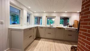 a large kitchen with white cabinets and windows at Family summerhouse in Kurepalu +43 photos
