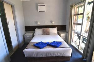 a bedroom with a bed with blue towels on it at Narooma Motel in Narooma