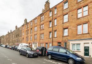 una fila de autos estacionados frente a un edificio de ladrillo en King's Road - 425, en Edimburgo