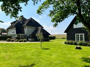 una casa en blanco y negro con un patio de césped en Villa Nieuwland B&B en Den Oever