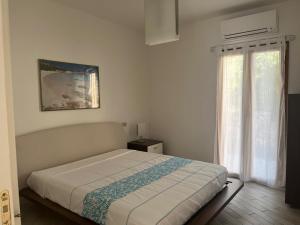 a white bedroom with a bed and a window at Da Masciu in La Maddalena