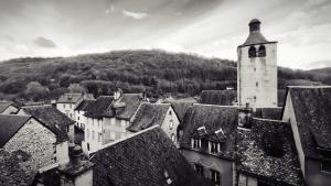 Una fotografía en blanco y negro de una ciudad con una torre de reloj. en L'échappée belle de l'Aubrac, en Saint-Chély-dʼAubrac