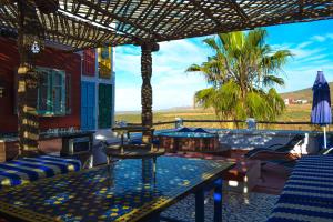 a patio with tables and chairs and a palm tree at Ocean View 6 bed Villa and Pool in Mirleft