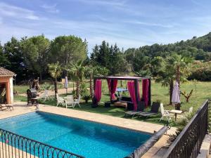 a pool with a gazebo and chairs next to it at Le petit ribbas in Le Cannet-des-Maures