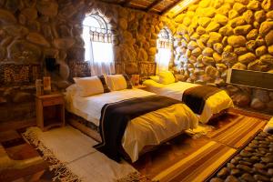 two beds in a room with a stone wall at Tambo Coquesa Lodge in Coquesa