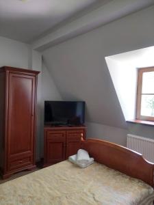Wola ChojnataにあるPałac Chojnataのベッドルーム1室(ベッド1台、テレビ付)、木製キャビネットが備わります。