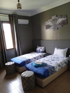 1 dormitorio con 2 camas con sábanas azules y ventana en Complex Amazon Guercif, en Guercif