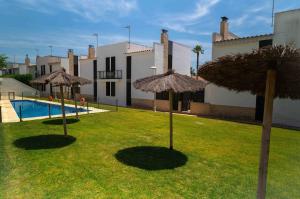 two straw umbrellas in the grass in front of a house at ¡Las Brisas en Conchas del Rompido! - El Rompido in El Rompido