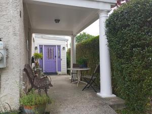 une terrasse couverte avec une porte violette et une table avec des chaises dans l'établissement Bryn Mawr Guest Suites, à Bryn Mawr