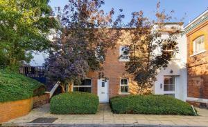a brick house with a white door and trees at Wild Roses Serviced Apartments - City Airport in North Woolwich