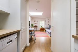 a kitchen and living room with white cabinets and a table at Wild Roses Serviced Apartments - City Airport in North Woolwich