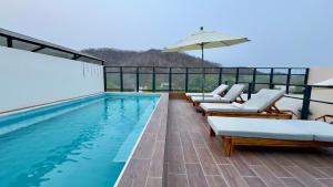 a swimming pool with lounge chairs and an umbrella at Nabani Condominios T2 in Santa Cruz Huatulco
