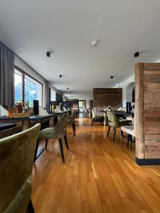 a dining room with wooden floors and tables and chairs at Biovita Hotel Alpi in Sesto