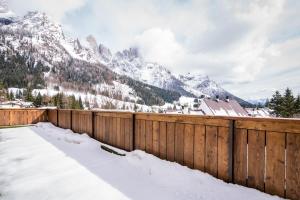 a fence covered in snow with mountains in the background at Hotel Colfosco in San Martino di Castrozza