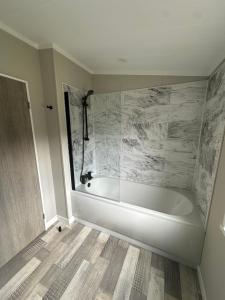 a white bath tub in a bathroom with marble at Cackle hill lakes, heron lodge in Biddenden +8 photos