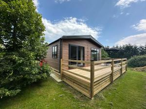 a tiny house with a deck in a yard at Cackle hill lakes, heron lodge in Biddenden