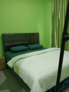 a bed in a room with a green wall at Mentigen Homestay in Ngadisari