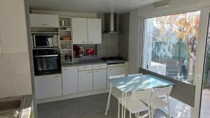 MontbazinにあるLe loftの白いキャビネットとテーブルと窓のあるキッチン