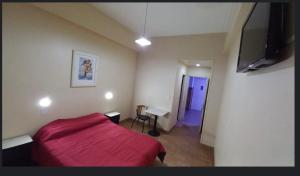ブエノスアイレスにあるHotel Litoral CERCA DE MOVISTAR ARENAのベッドルーム(赤いベッド1台、テレビ付)