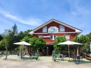 a red building with tables and chairs and umbrellas at Alojamiento casa pepe in Soto de Cangas